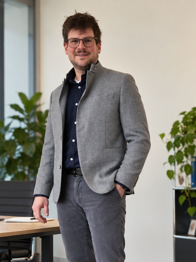 Patrick Haas im grauen Sakko in einem hellen Büro
